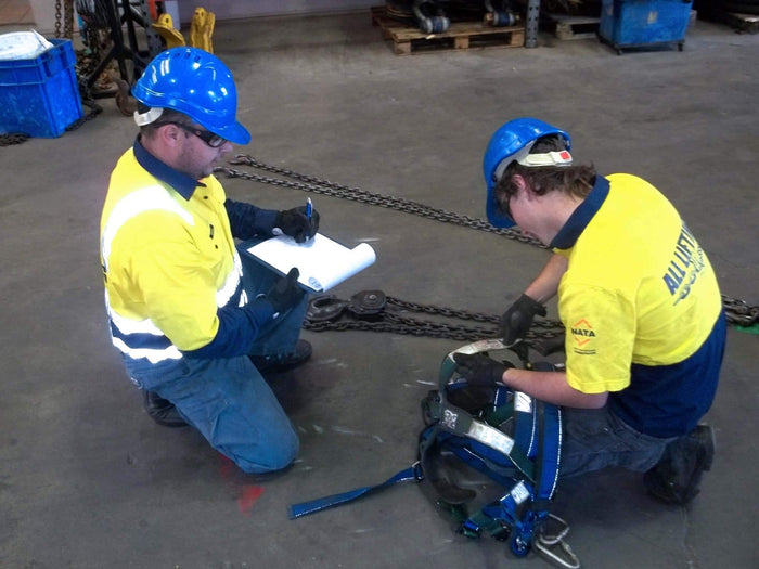 Workers conducting a lifting equipment risk assessment in a warehouse setting.